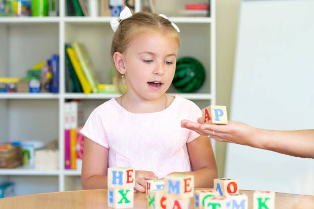 istock developmental and speech therapy classes with a child-girl. Speech therapy exercises and games with letters. dice game 1406864760