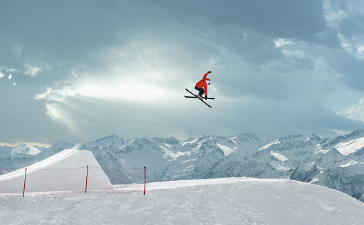 Side view of young male ski jumper during the long ski jump against the blurred background