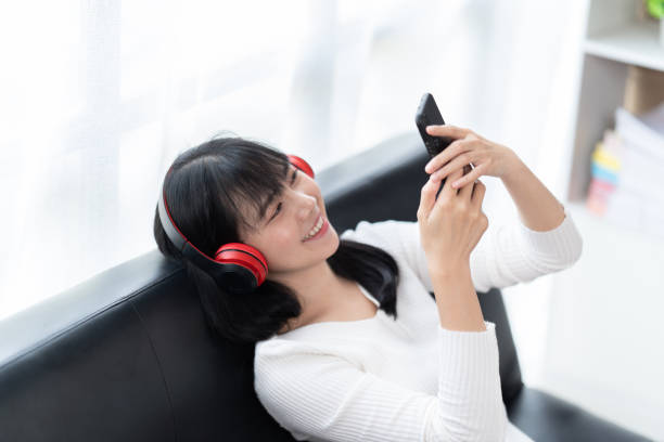 istock Happy young woman using smartphone at home sitting on soft couch, she is using a smartphone and texting, technology and communication concept. 1406864948
