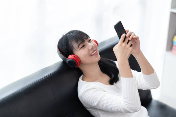 istock Happy young woman using smartphone at home sitting on soft couch, she is using a smartphone and texting, technology and communication concept. 1406865826