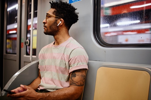 Young man riding a subway train while holding his mobile phone
