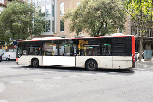 A large city bus with a blank advertisement panel on its side