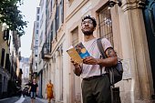 Young man using city guide while exploring European city