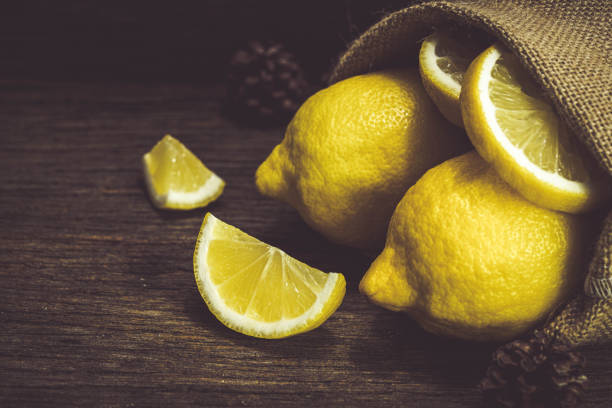 istock Group of fresh yellow lemon fruit on wood background with burlap 1406868795