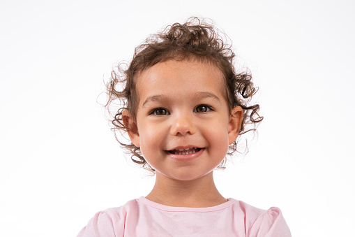 Cute little girl in pink dress smiling at camera