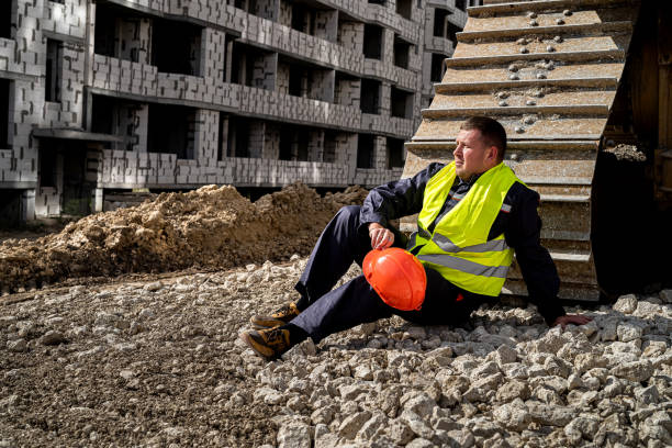 istock a strong worker in uniform sits on an open ground with a stone grader 1406870489