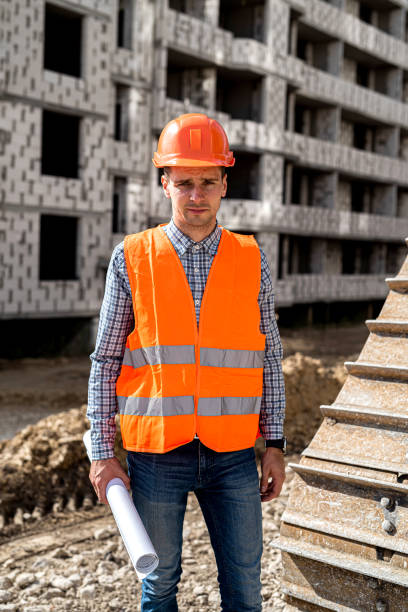 istock a strong man working in uniform and helmet stands under an unfinished house 1406870635