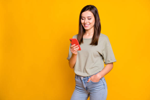 istock Portrait of attractive cheerful focused girl using gadget app browsing multimedia isolated over bright yellow color background 1406872098
