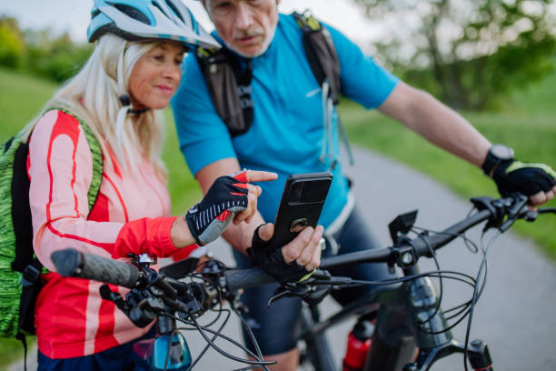 istock Active senior couple resting after bicycle ride at summer park, using smartphone. 1406872239