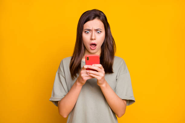 istock Portrait of lovely confused focused brown-haired girl using device browsing web isolated over bright yellow color background 1406872495