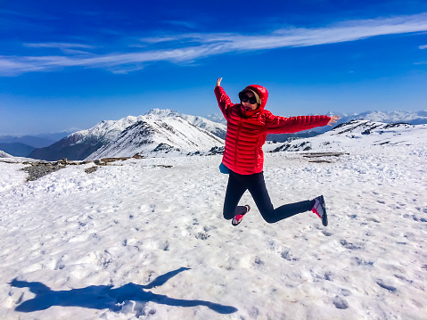 Happy woman on top of mountain in snow