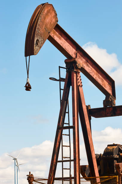 istock Oil pumping machine and windmills. Petroleum extraction. Global warming 1406876426