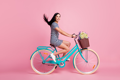 Full length body size profile side view of attractive cheerful girl riding vintage blue bike having fun isolated on pink pastel color background.