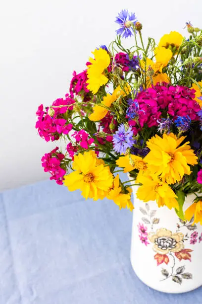Beautiful summer bouquet of carnations, cornflowers and yellow chamomiles, part of home interior