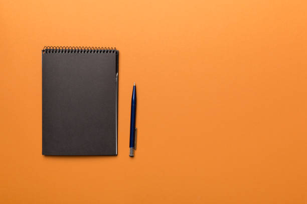 istock school notebook on a colored background, spiral black notepad on a table Top view 1406881169