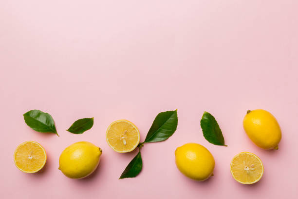 istock Many fresh ripe lemons with green leaves on colored background, top view, space for text 1406881183