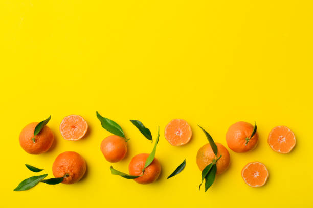 istock Many fresh ripe mandarin with green leaves on colored background, top view, space for text 1406881247