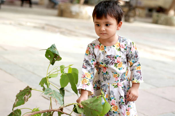 Small baby girl playing outdoors with nature leaf.