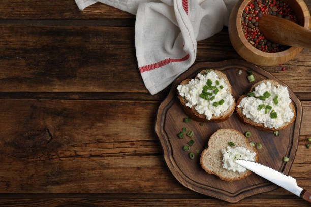 istock Bread with cottage cheese and green onion on wooden table, flat lay. Space for text 1406882107