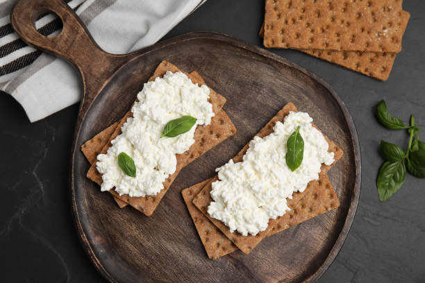 istock Crispy crackers with cottage cheese and basil on black table, flat lay 1406882486