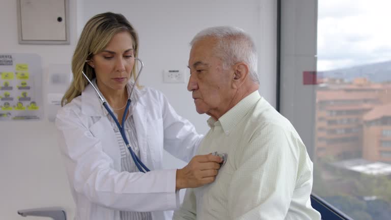 Female geriatrics doctor examining a male patient with a stethoscope