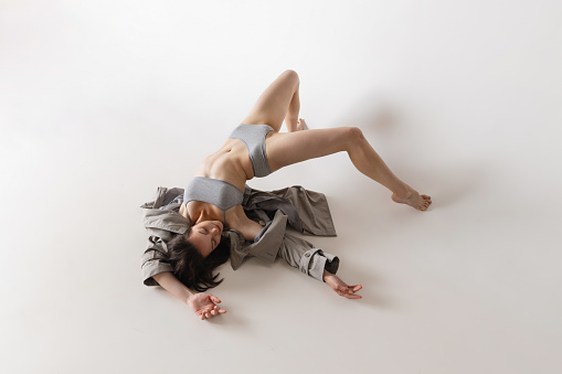 Feelings. Aerial view of young sensual woman in lingerie and coat dancing isolated on grey background. Art, motion, action, flexibility, inspiration concept. Solo performance