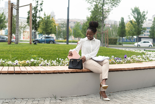 Portrait of a beautiful African American businesswoman sitting outdoors and checking some documents