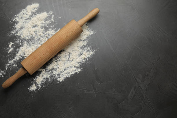 istock Rolling pin and flour on black table, top view. Space for text 1406887302
