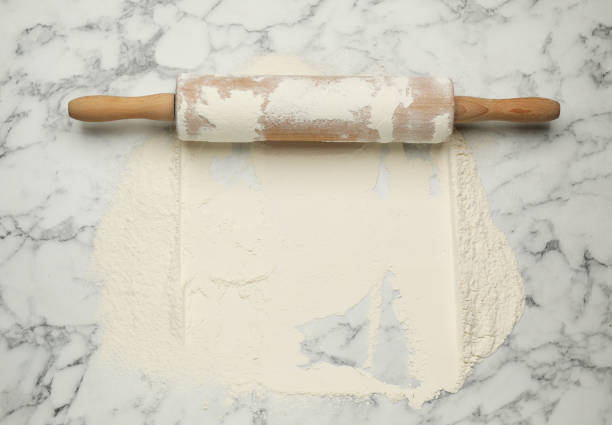 istock Rolling pin and flour on white marble table, top view. Space for text 1406887318