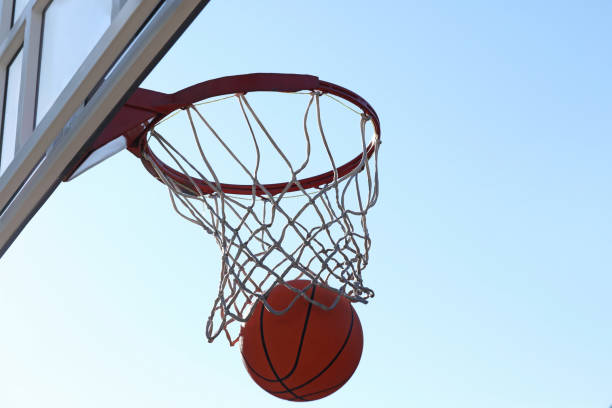 istock Basketball ball and hoop with net outdoors on sunny day 1406887468