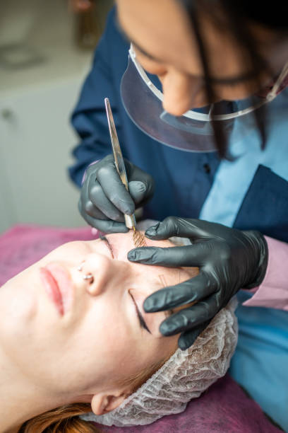 istock Procedure of eyebrow microblading. A master in black gloves is doing a blending needle of model's brow. 1406887573