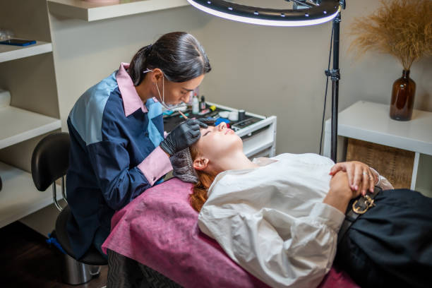 istock Procedure of eyebrow microblading. A master in black gloves is doing a blending needle of model's brow. 1406887652