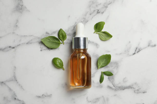 istock Bottle of essential basil oil and fresh leaves on white marble table, flat lay 1406887656