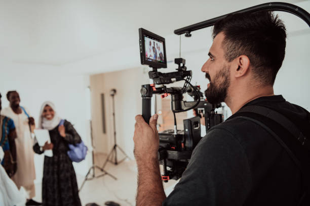 istock A videographer in a home studio captures a group of modern students with a professional camera. 1406889006