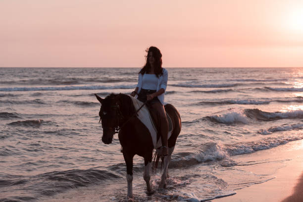 istock Woman in summer clothes enjoys riding a horse on a beautiful sandy beach at sunset. Selective focus 1406890708