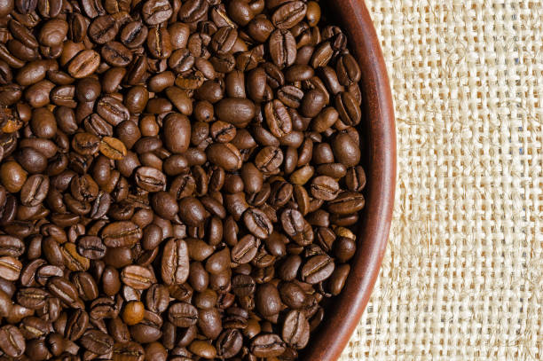 istock Roasted coffee beans on a ceramic plate close-up on burlap. 1406891200