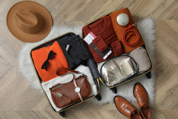istock Open suitcase with folded clothes, accessories and shoes on floor, flat lay 1406891518