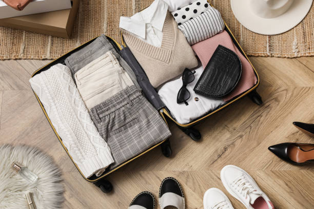 istock Open suitcase with folded clothes, accessories and shoes on floor, flat lay 1406891565