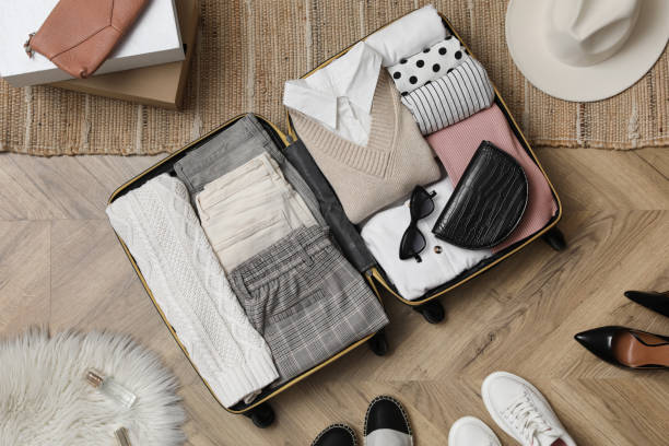 istock Open suitcase with folded clothes, accessories and shoes on floor, flat lay 1406891649