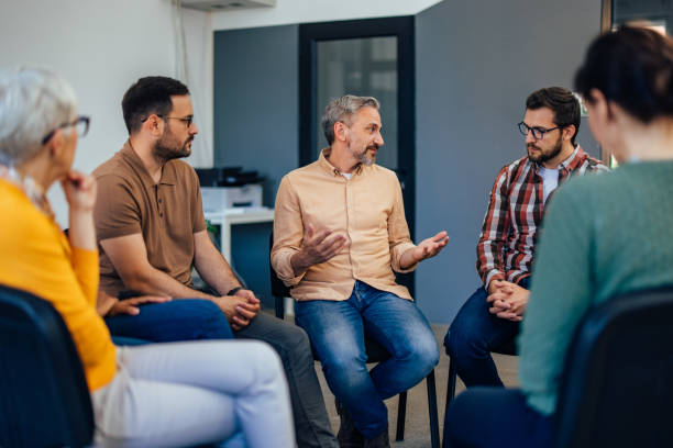 istock Three males sitting next to each other, talking to the others from the group therapy. 1406891881