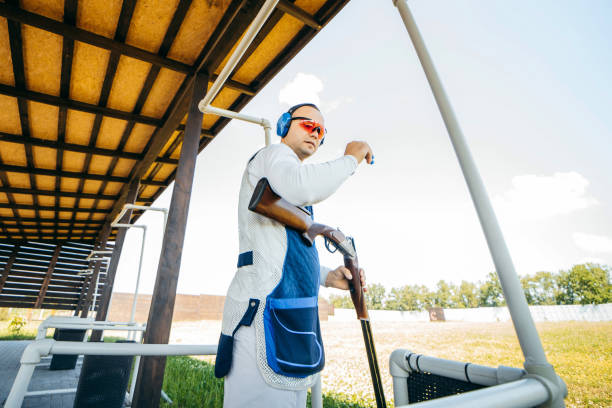 erwachsener mann mit sonnenbrille, schützenden kopfhörern und einer gewehrweste, der das schießen mit feuerwaffen übt. - sport clipping path handgun pistol stock-fotos und bilder