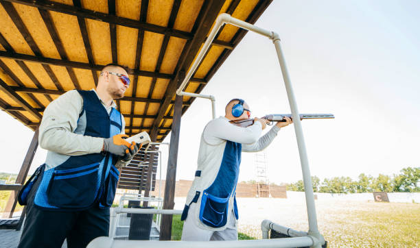 ein schütze hält eine fernbedienung zum starten von zielen, und der zweite schütze zielt auf sie - sport clipping path handgun pistol stock-fotos und bilder