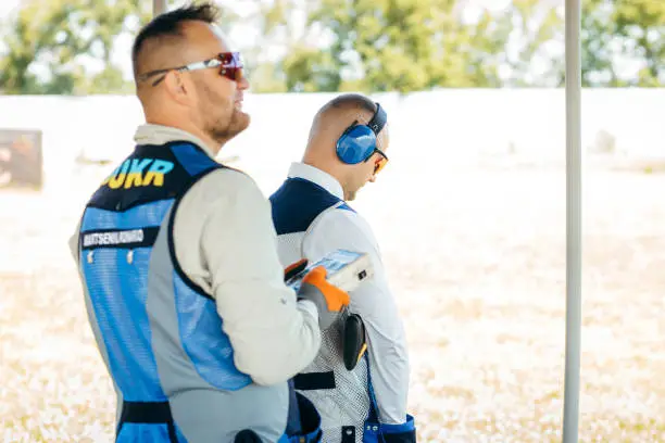 Photo of One shooter holds a remote control for launching targets, and the second shooter aims at them