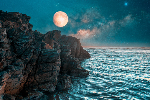 full moon over the cliff and ocean at night