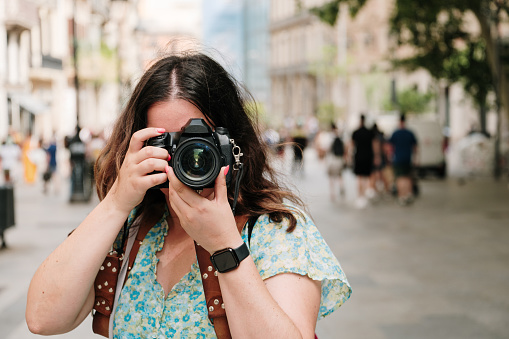 A young tourist taking a picture with a DSLR camera in a city