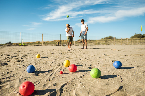 image of a volleyball sitting in the sand with net in background