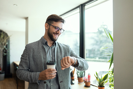 Businessman in office drinking coffee using phone