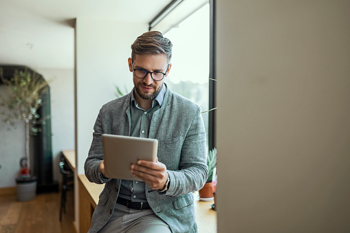 Businessman in office drinking coffee using phone