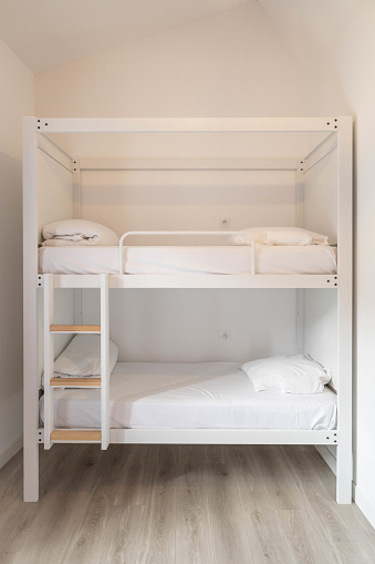 White bunk beds with stairs, in a white room