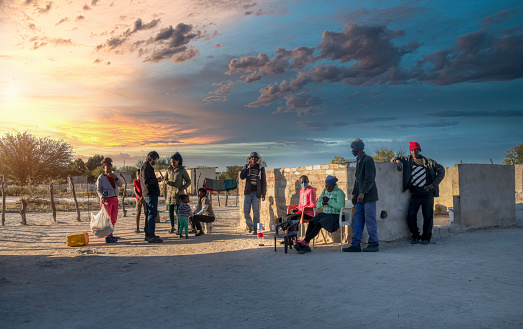 Extended African family talking with a Caucasian man in the yard of a house in a village in Botswana